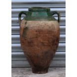 A green glazed two-handled terracotta olive jar of tapering cylindrical form, 51cms high.