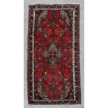 A Persian runner with central medallion and floral decoration on a red ground within a multi border,