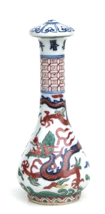 A Chinese Wucai porcelain calligraphy brush handle decorated with a dragon amongst clouds chasing