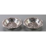 A pair of pierced and embossed silver bonbon dishes with central cherub within a foliate border,