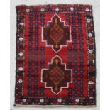 A Persian prayer rug with two central guls on a red ground within a multi border, 135 by 85cms.
