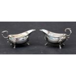 A pair of George III style silver sauce boats with gadrooned rims, scroll handles and shell capped