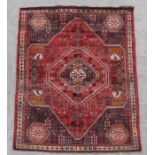 A large Persian rug with central medallion on a red ground surrounded by repeating floral images