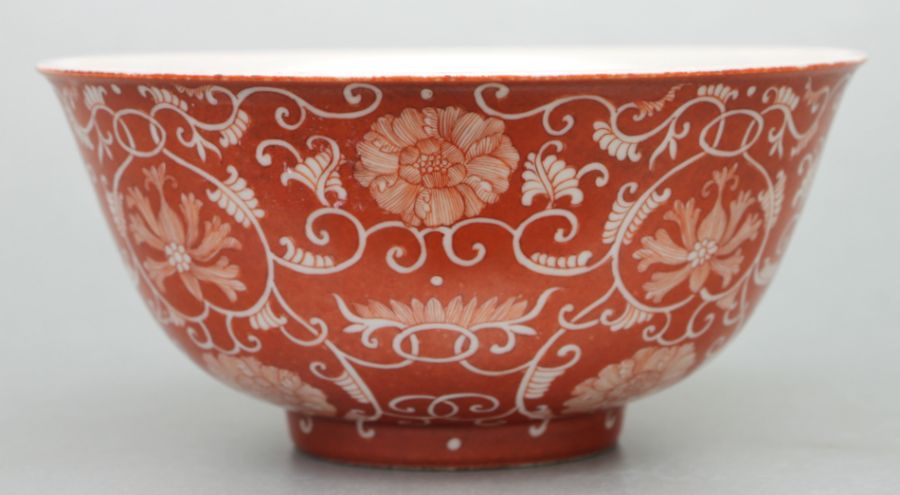 A Chinese footed bowl decorated with scrolling flowering foliage on a burnt orange ground, six