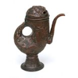 A Tibetan copper water jug or ewer decorated with scrolling stylised dragons with pierced mask