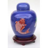 A Chinese powder blue ginger jar and cover decorated with fish, on a hardwood stand, 28cms high.