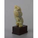 A Chinese jade / hardstone figural group depicting a robed man with a monkey on his back, on a