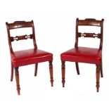 A pair of Victorian mahogany dining chairs with carved back rails, overstuffed seats, on turned