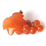 A yellow metal mounted (stamped 18k) amber brooch in the form of grapes and vine leaf.