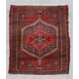 A Persian Hamadan hand knotted woollen rug with stylised design within borders, on a red ground, 140