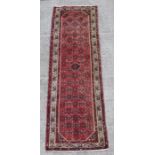 A Persian runner with geometric design on a red ground within a multi border, 282 by 81cms.