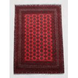 A Persian Turkoman woollen hand knotted rug with repeat design on a red ground, 237 by 155cms.