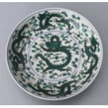 A Chinese famille vert shallow footed bowl decorated with dragons amongst clouds chasing a flaming