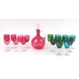 A cranberry glass decanter, 25cms high; together with a harlequin set of cranberry green and blue