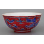 A Chinese footed bowl decorated with dragons chasing a flaming pearl, on a red ground, six character