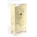 A Chinese style lacquer two-door cupboard decorated with flowers and birds, 59cms wide.