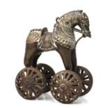 A late 19th century Indian bronze horse toy raised on four pierced wheels, 19cms high.