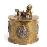 A WWI trench art tobacco jar and over with applied cap badges including RF, American North West