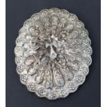 An Indian white metal mounted hand mirror decorated with a peacock, 18 by 15cms.