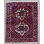 A Persian rug with two guls on a red ground. 147 by 199cm