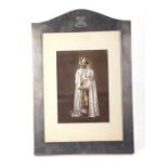 A large unmarked silver photo frame surmounted with an Indian crest, containing a coloured black &