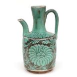 A Chinese pottery wine ewer decorated with foliate scrolls on a green ground, 24cms high.