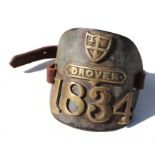 An early 19th century brass drover's armband with leather strap, numbered 1834, 11cms high.