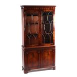 A Georgian style mahogany bookcase on cupboard, the pair of glazed doors enclosing a shelved