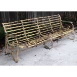 A large well weathered wrought iron garden bench, 237cms wide.