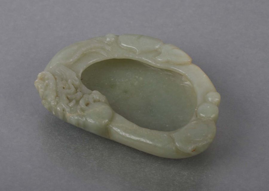 A Chinese jade / hardstone brush washer decorated with a dragon and lily pads, on a hardwood