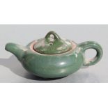 A Chinese monochrome green glazed pottery teapot of compressed globular form, 14cms long.