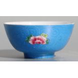 A Chinese famille rose footed bowl decorated with flowers on a sgrafitto decorated blue ground,