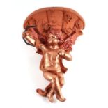 A moulded composition faux terracotta cherub wall pocket, 43cms high.