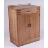 A Heals style limed oak cupboard with single frieze drawer above two panelled doors, 68cms wide;