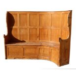 A large pine settle with bow backed with shaped end supports, the box base with lift-up seats