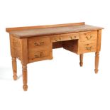 A pine kneehole desk with an arrangement of five drawers, on turned front legs, 152cms wide.