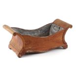 A 19th century mahogany cheese coaster with scroll ends, converted to a planter with associated zinc