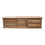 A large stripped pine dresser base with a central cupboard flanked by two banks of two long drawers,