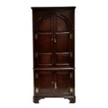 A George III oak floor standing corner cupboard, the pair of arched panelled doors enclosing a