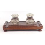 A late Victorian / early Edwardian carved oak pen and ink stand inset with two cut glass inkwells,