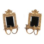 A pair of gilt brass twin-branch mirror backed girandole with ornate dolphin decoration, each