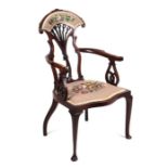 An Art Nouveau mahogany armchair with carved and upholstered pierced fan shaped back splat, scroll