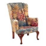 A country house George II style upholstered wing back armchair on carved shell capped dwarf cabriole