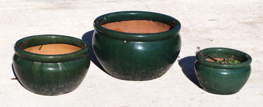 A set of three green glazed terracotta pots, the largest 45cms diameter (3).