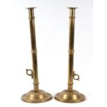 A pair of Georgian brass ejector candlesticks with long slender stems terminating in stepped