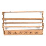 A continental painted pine hanging wall shelves with turned supports and panelled back, 100cms wide;