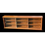 A teak wall hanging display cabinet with glazed sliding doors enclosing a shelved interior, 182cms