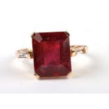 A 9ct gold dress ring set with a large rectangular red stone and baguette cut diamond set shoulders,