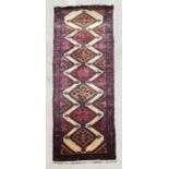 A Persian hand knotted woollen runner with stylised diamond motifs on a beige ground, 265 by