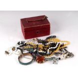 A quantity of costume jewellery in a red leather jewellery box.